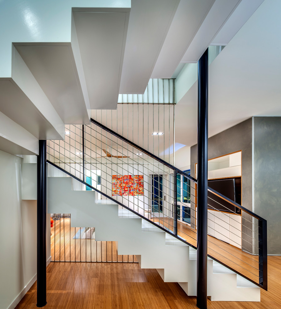 Ejemplo de escalera suspendida moderna grande con barandilla de metal, escalones con baldosas y contrahuellas con baldosas y/o azulejos