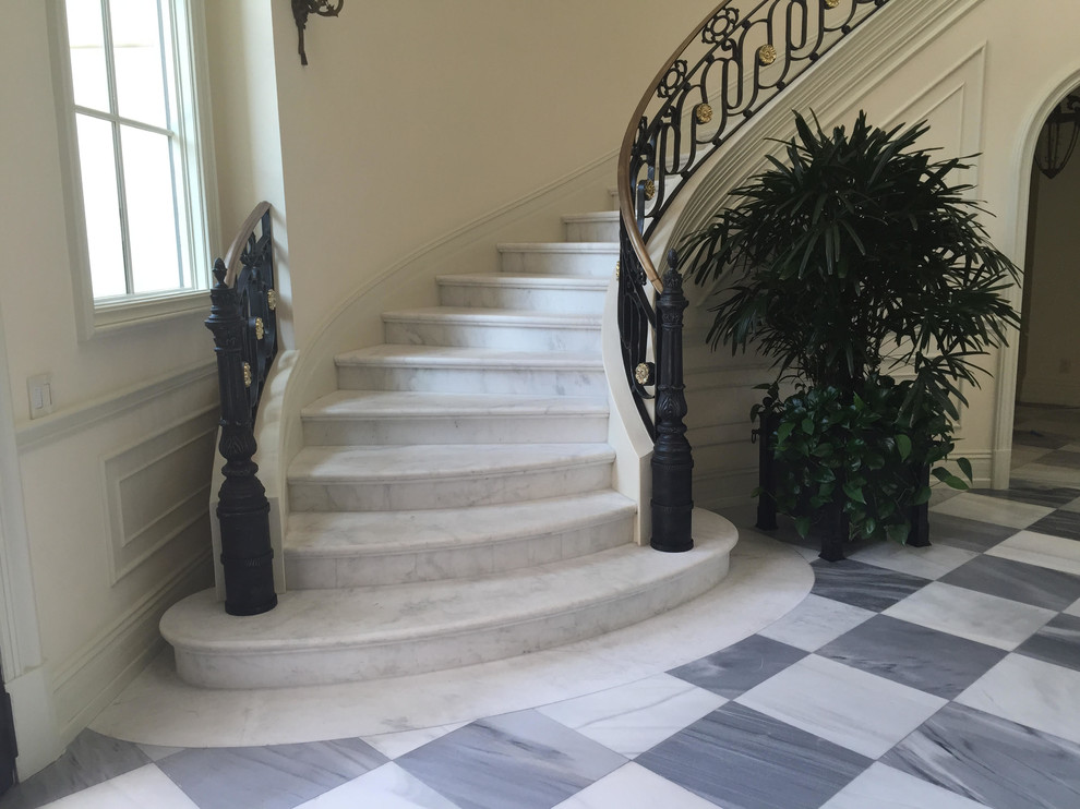 Inspiration för stora klassiska svängda trappor i marmor, med sättsteg i marmor och räcke i metall