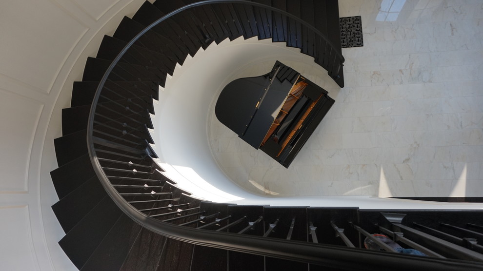 ヒューストンにあるラグジュアリーな広いコンテンポラリースタイルのおしゃれなサーキュラー階段 (フローリングの蹴込み板、金属の手すり) の写真