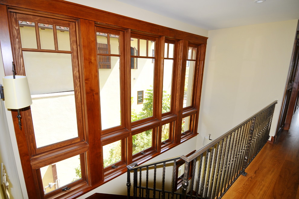 Ejemplo de escalera en U exótica de tamaño medio con escalones de madera, contrahuellas de madera y barandilla de metal