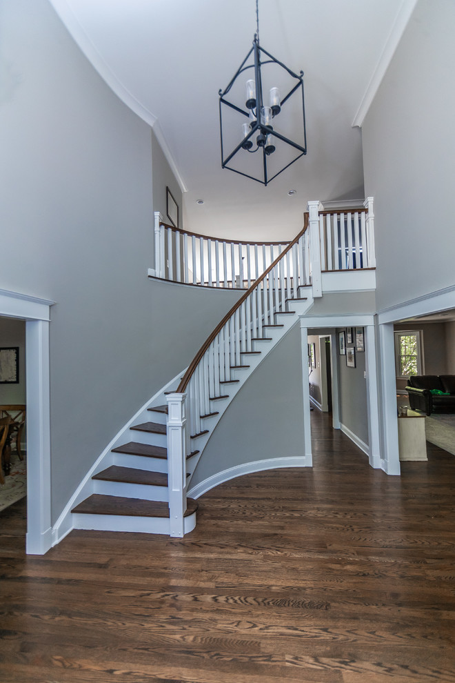 Cette image montre un grand escalier peint courbe craftsman avec des marches en bois et un garde-corps en bois.