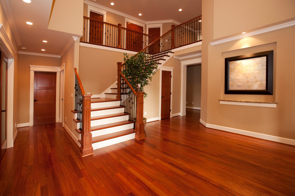 На фото: большая угловая лестница в классическом стиле с деревянными ступенями и крашенными деревянными подступенками с