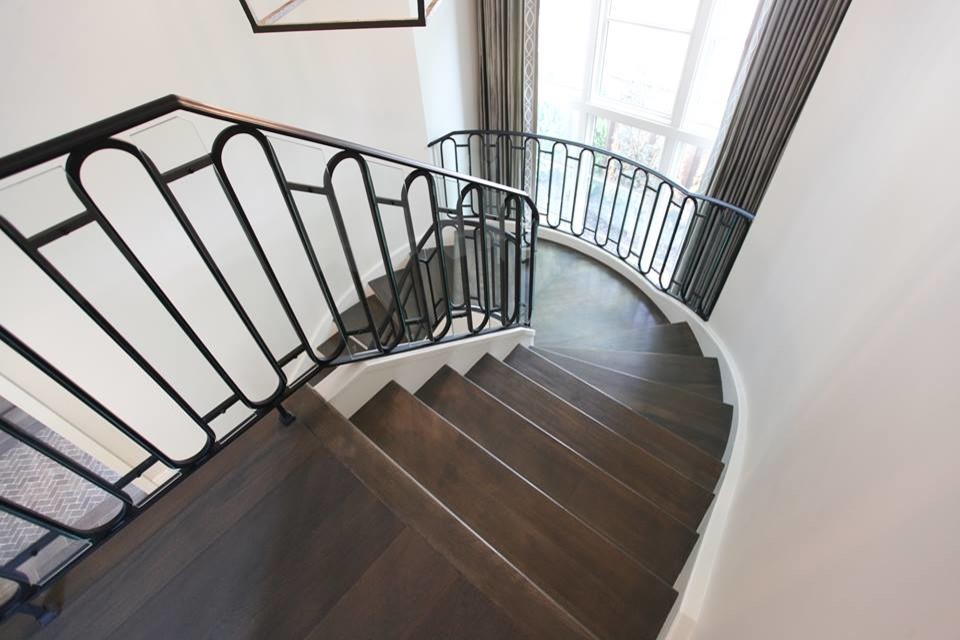 Ejemplo de escalera curva de estilo americano extra grande con escalones de madera