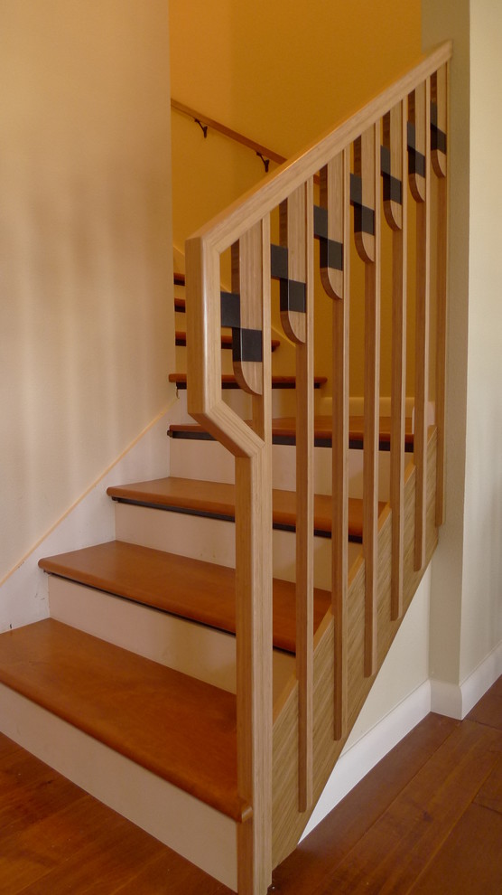 На фото: лестница в стиле модернизм с деревянными ступенями, крашенными деревянными подступенками и деревянными перилами с