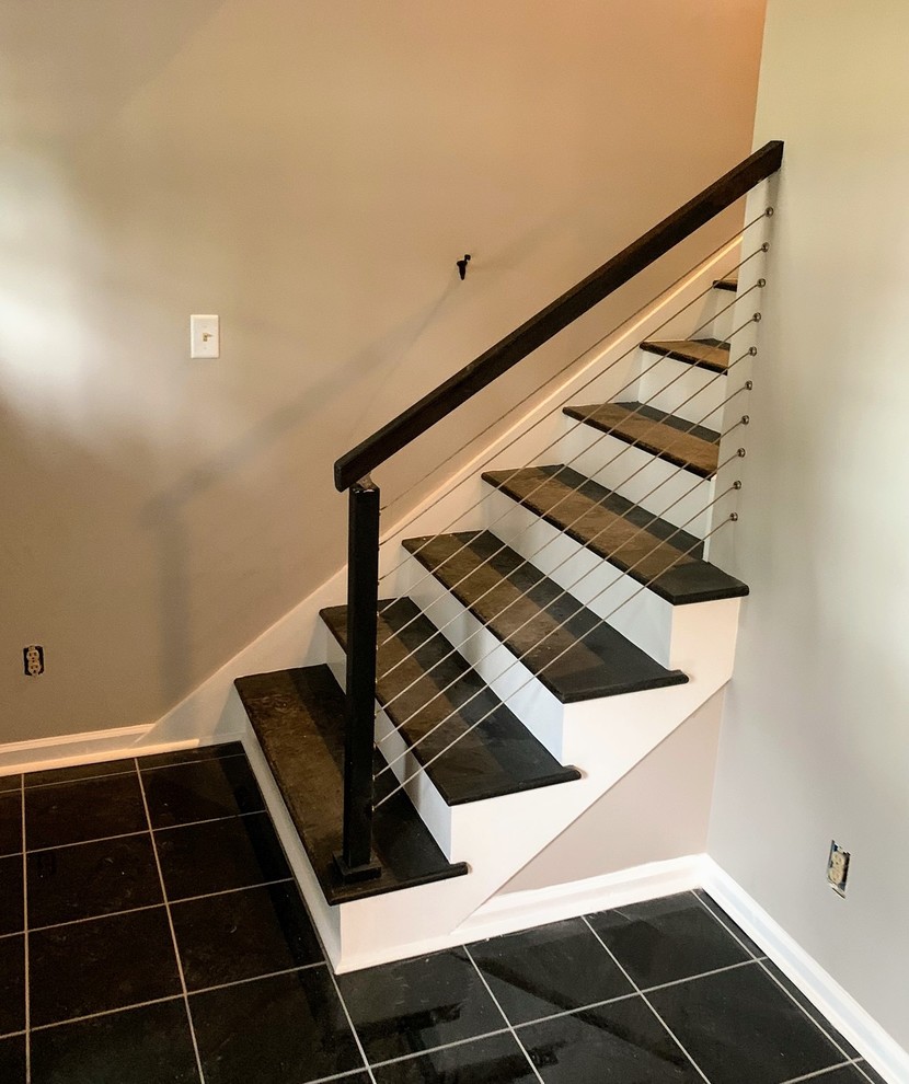 Ejemplo de escalera recta contemporánea de tamaño medio con escalones con baldosas, contrahuellas de madera pintada y barandilla de metal