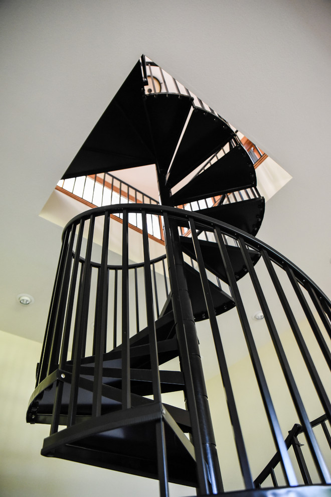 Cette image montre un escalier hélicoïdal vintage de taille moyenne avec des marches en métal, des contremarches en métal et un garde-corps en métal.