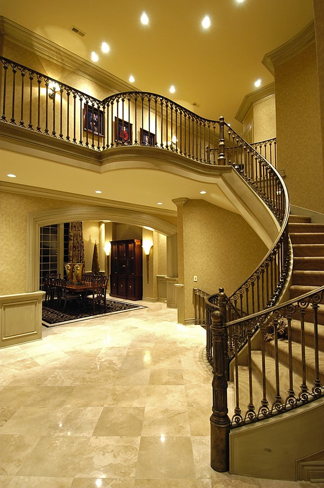 Пример оригинального дизайна: огромная изогнутая лестница в классическом стиле с ступенями с ковровым покрытием и ковровыми подступенками