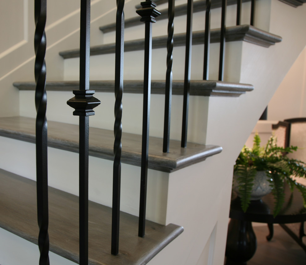 Идея дизайна: большая изогнутая лестница в классическом стиле с деревянными ступенями, крашенными деревянными подступенками и металлическими перилами