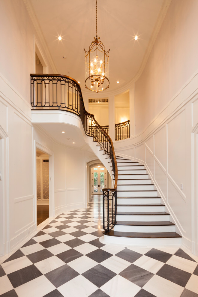 Foto de escalera curva, clásica, grande, con escalones de madera, contrahuellas de madera pintada y barandilla de varios materiales