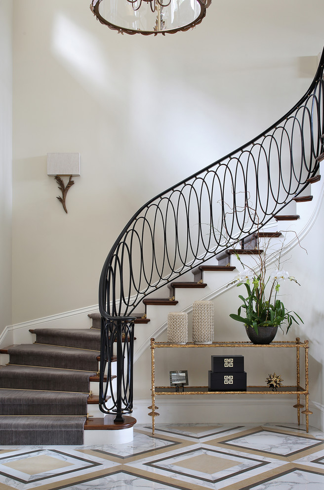 Foto de escalera curva clásica con escalones de madera, contrahuellas de madera pintada y barandilla de metal