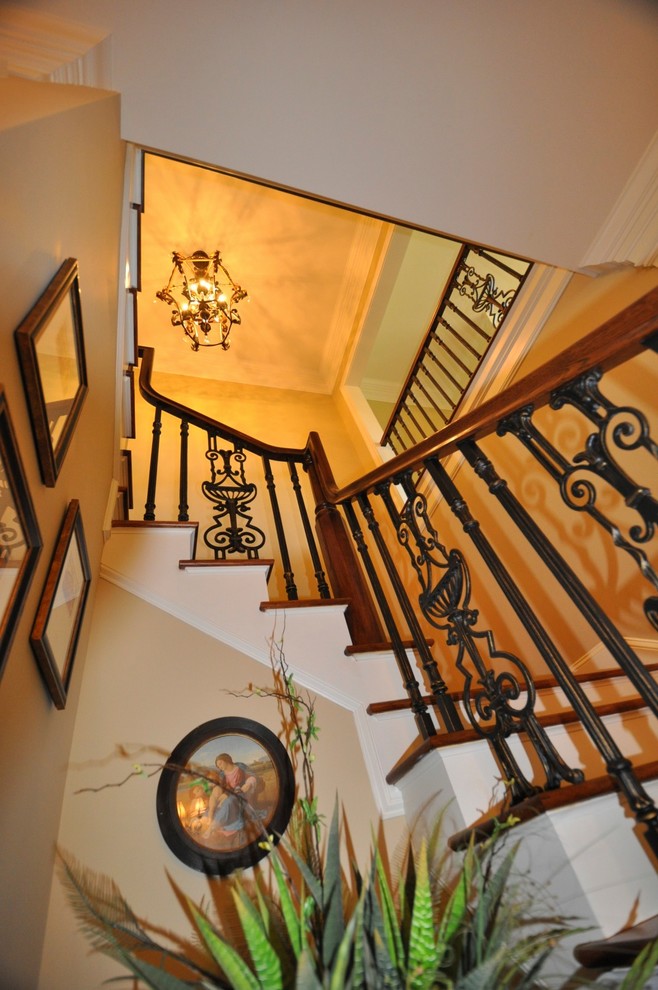 На фото: угловая лестница среднего размера в классическом стиле с деревянными ступенями, крашенными деревянными подступенками и металлическими перилами