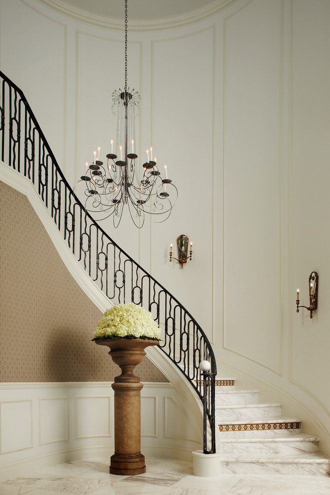 Diseño de escalera curva tradicional grande con escalones de mármol, contrahuellas de mármol y barandilla de metal