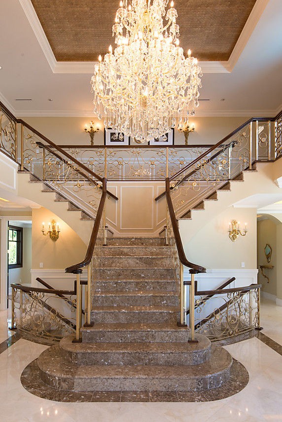 Large elegant marble l-shaped metal railing staircase photo in Vancouver with marble risers
