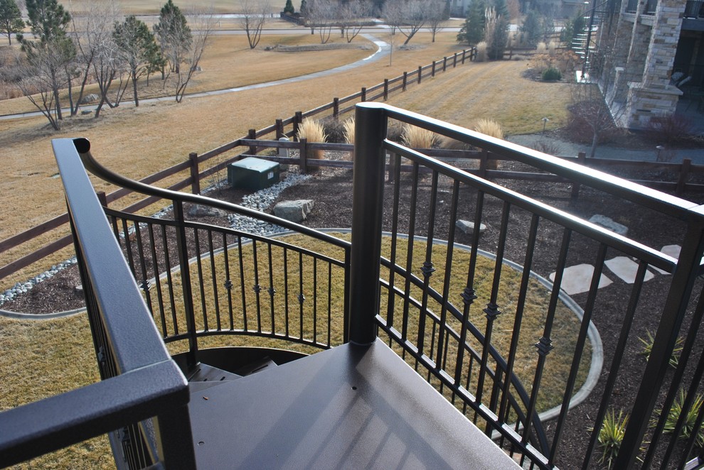 This is an example of a large traditional metal spiral metal railing staircase in Denver with open risers.
