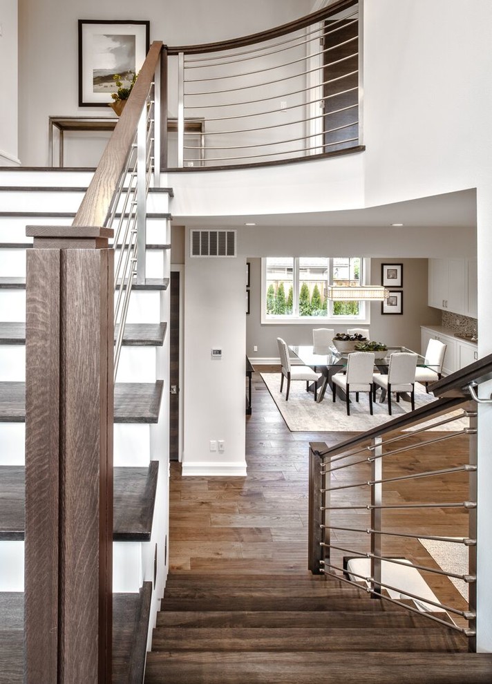 На фото: большая п-образная лестница в стиле неоклассика (современная классика) с деревянными ступенями, крашенными деревянными подступенками и перилами из тросов