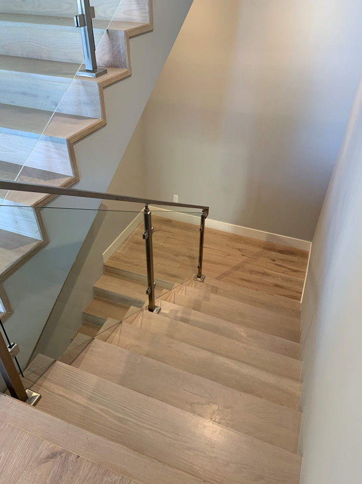 Foto de escalera en U tradicional renovada grande con escalones de madera, contrahuellas de madera y barandilla de vidrio
