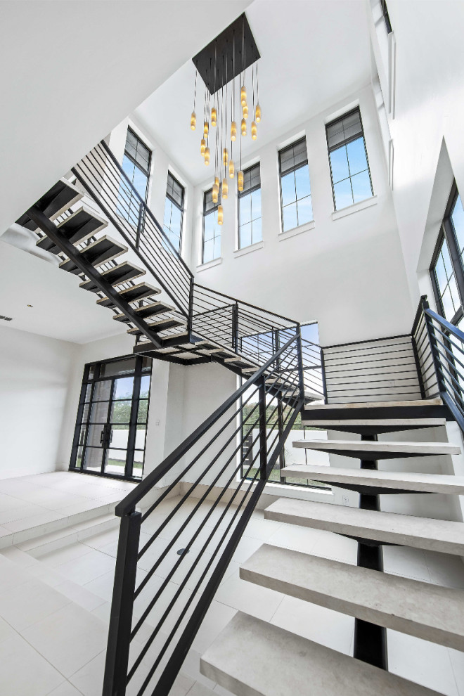 This is an example of a large classic floating metal railing staircase in Austin with limestone treads.