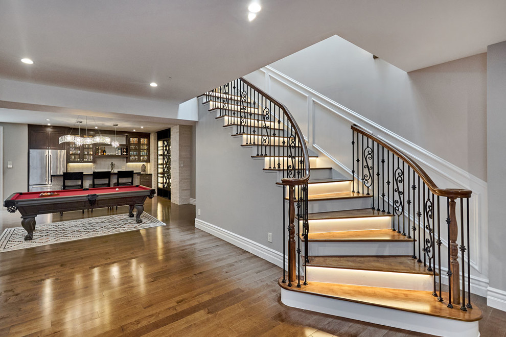 Example of a large transitional wooden curved metal railing staircase design in San Francisco with wooden risers