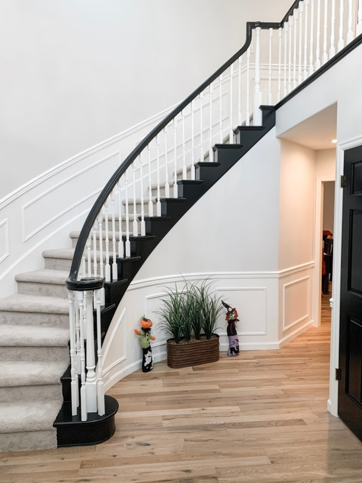 Идея дизайна: изогнутая лестница среднего размера в стиле неоклассика (современная классика) с ступенями с ковровым покрытием, ковровыми подступенками, деревянными перилами и панелями на стенах