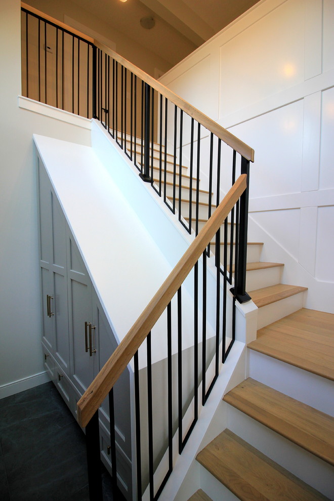 Стильный дизайн: большая угловая лестница в стиле неоклассика (современная классика) с деревянными ступенями, крашенными деревянными подступенками и перилами из смешанных материалов - последний тренд