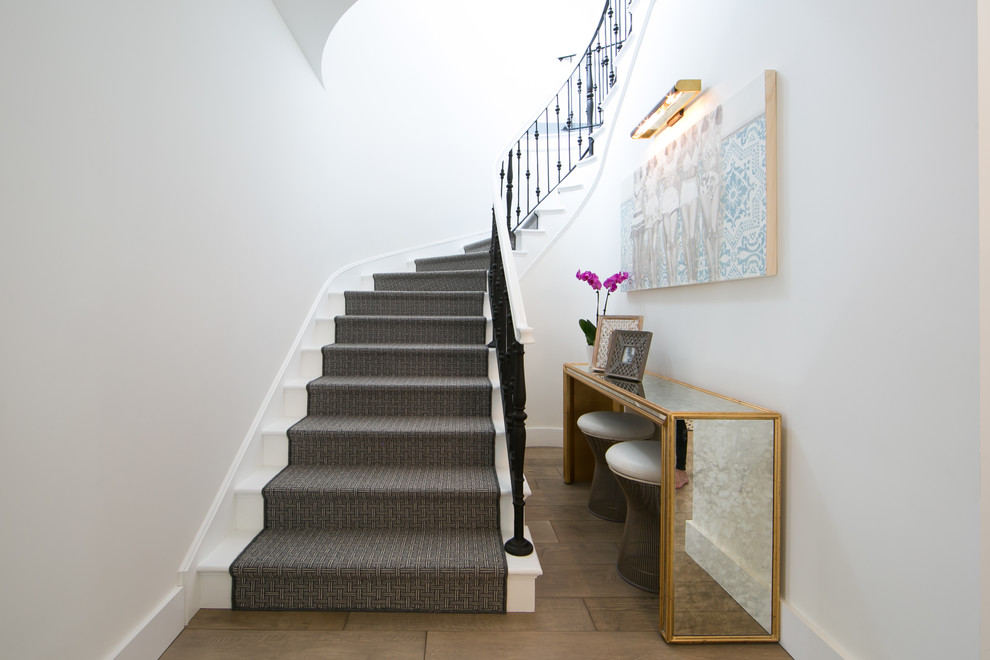 На фото: изогнутая лестница в стиле неоклассика (современная классика) с крашенными деревянными ступенями и крашенными деревянными подступенками с