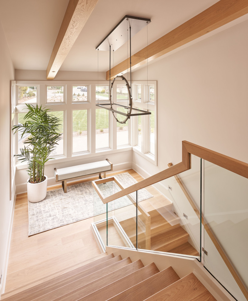 Свежая идея для дизайна: п-образная деревянная лестница в стиле неоклассика (современная классика) с деревянными ступенями и стеклянными перилами - отличное фото интерьера