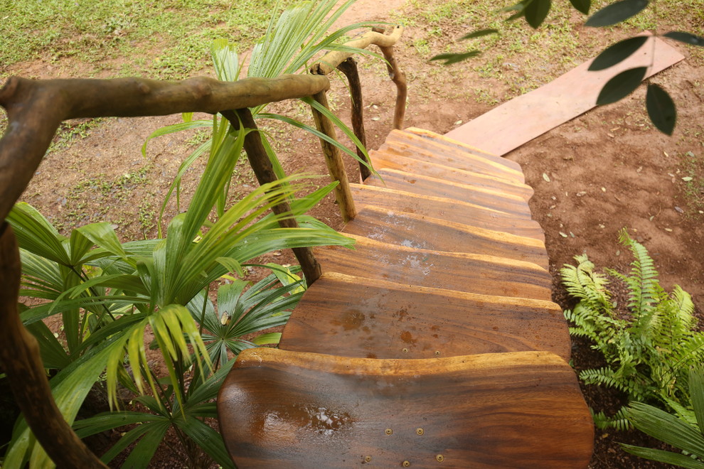Foto på en liten tropisk rak trappa i trä, med öppna sättsteg och räcke i trä