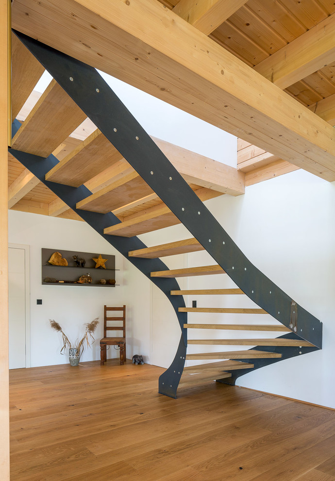На фото: большая изогнутая лестница в современном стиле с деревянными ступенями без подступенок с