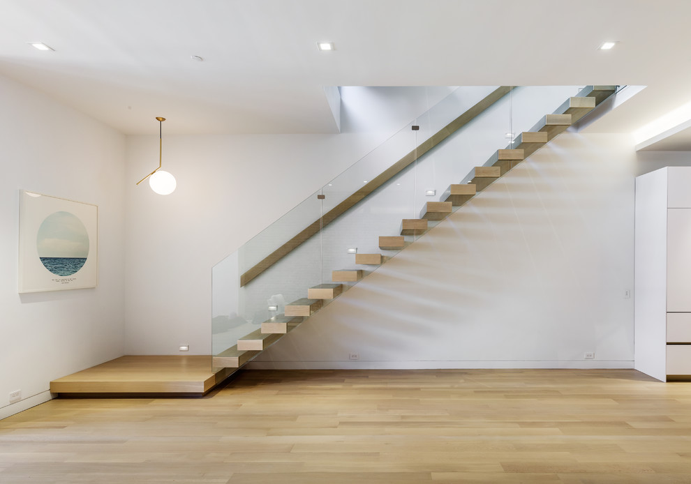 На фото: прямая лестница в современном стиле с деревянными ступенями и стеклянными перилами без подступенок