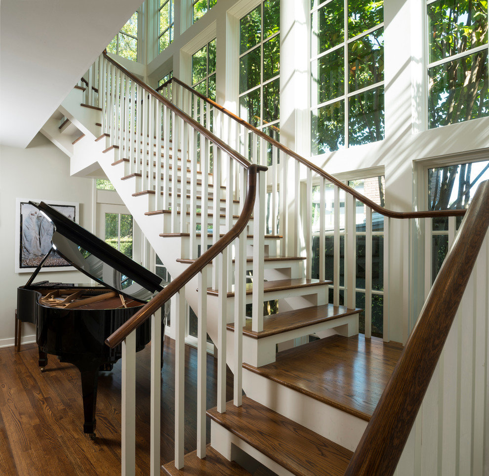 Imagen de escalera en L de estilo americano grande sin contrahuella con escalones de madera y barandilla de madera