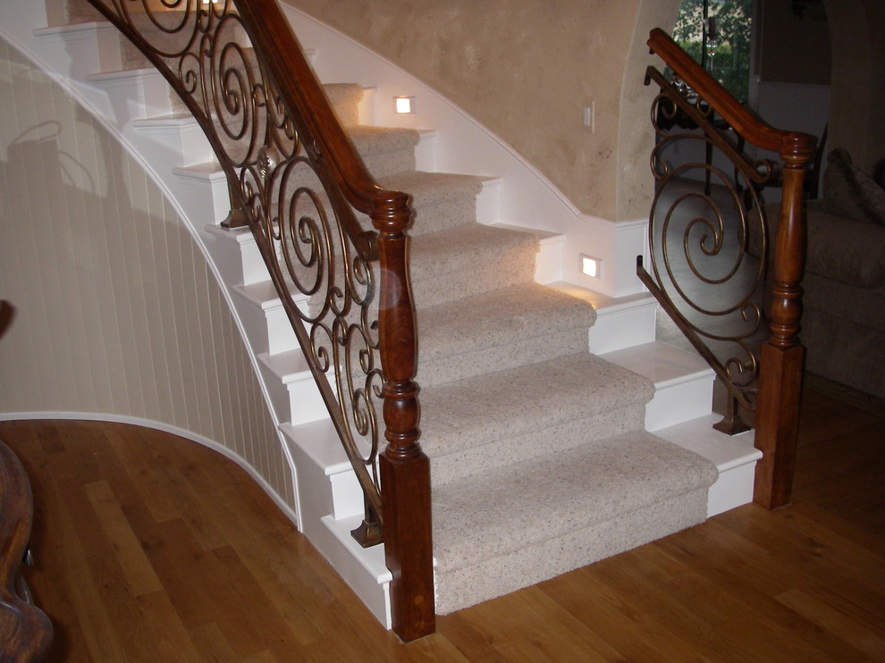 Пример оригинального дизайна: изогнутая лестница в средиземноморском стиле с крашенными деревянными ступенями и крашенными деревянными подступенками