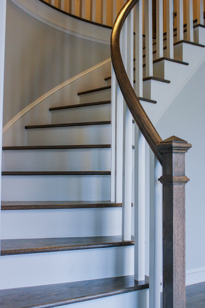 Источник вдохновения для домашнего уюта: изогнутая лестница в стиле неоклассика (современная классика) с деревянными ступенями, крашенными деревянными подступенками и деревянными перилами