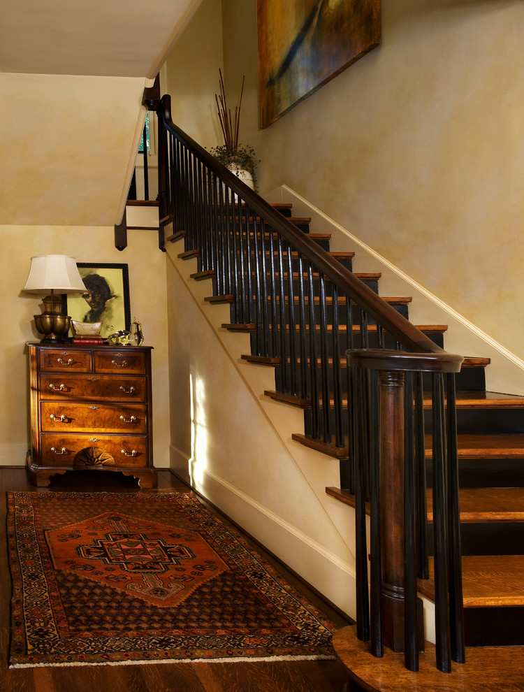 На фото: угловая лестница в классическом стиле с деревянными ступенями, крашенными деревянными подступенками и деревянными перилами с