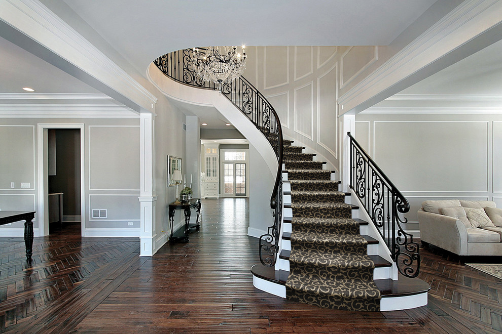 Cette photo montre un très grand escalier peint courbe chic avec des marches en bois et un garde-corps en métal.