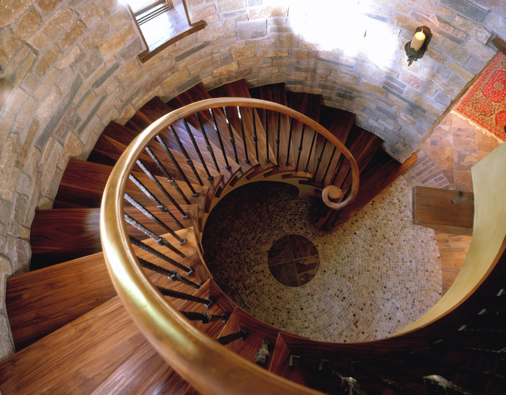 Imagen de escalera de caracol de estilo americano grande con escalones de madera, contrahuellas de madera y barandilla de varios materiales