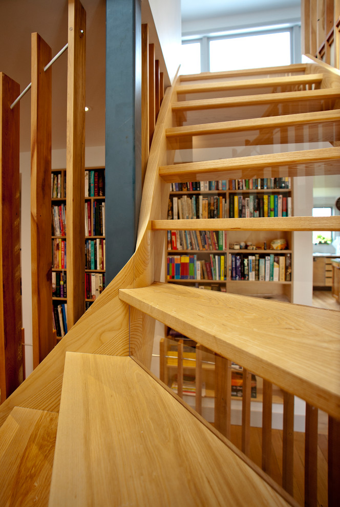 Стильный дизайн: большая изогнутая деревянная лестница в современном стиле с деревянными ступенями и деревянными перилами - последний тренд