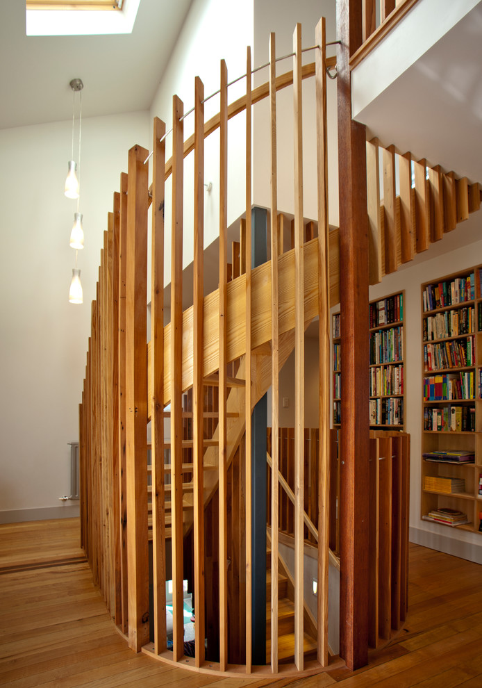 Пример оригинального дизайна: большая изогнутая деревянная лестница в современном стиле с деревянными ступенями и деревянными перилами