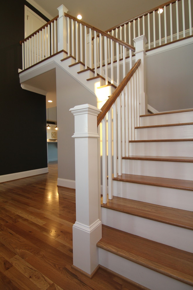 Imagen de escalera en L actual grande con contrahuellas de madera pintada y escalones de madera