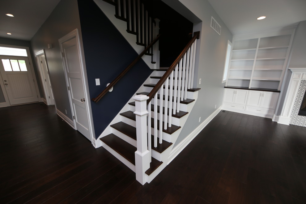 Imagen de escalera en U de estilo americano grande con escalones de madera, contrahuellas de madera y barandilla de madera