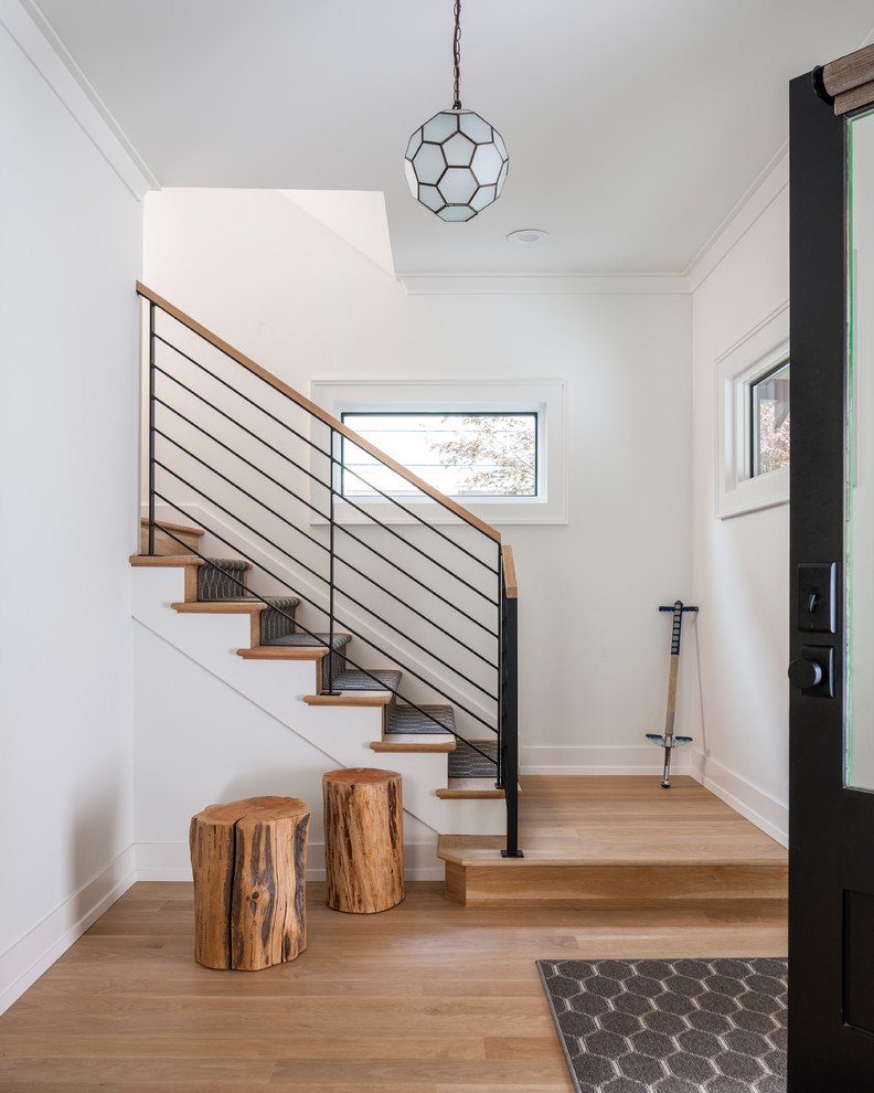 На фото: прямая деревянная лестница среднего размера в стиле неоклассика (современная классика) с деревянными ступенями и металлическими перилами с