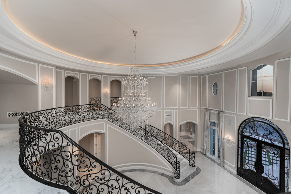 Идея дизайна: огромная изогнутая лестница в стиле неоклассика (современная классика) с мраморными ступенями, подступенками из мрамора и перилами из смешанных материалов