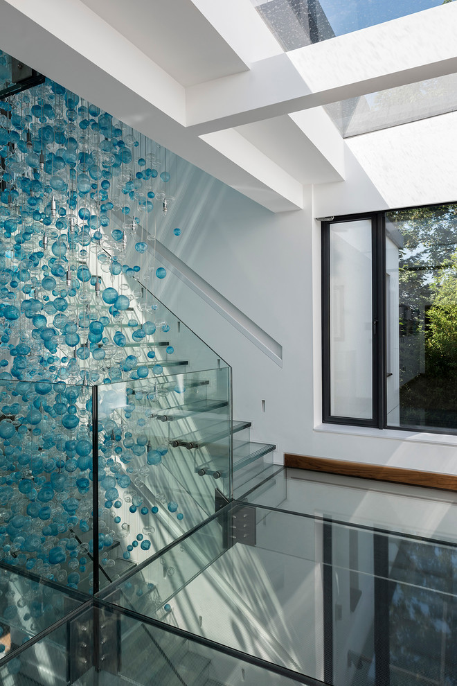 Aménagement d'un grand escalier flottant contemporain avec des marches en verre et des contremarches en verre.