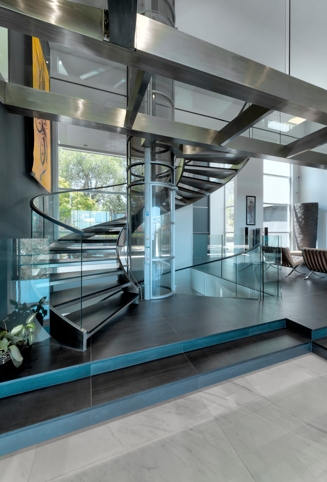 Источник вдохновения для домашнего уюта: огромная винтовая лестница в современном стиле с стеклянными перилами без подступенок