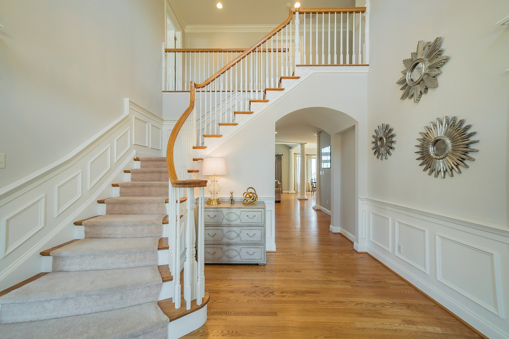 Large elegant wooden curved wood railing staircase photo in Philadelphia with wooden risers