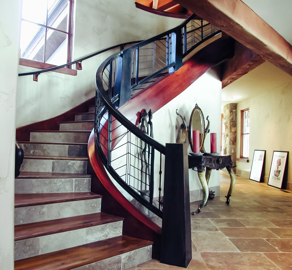 Ejemplo de escalera curva rústica de tamaño medio con escalones de madera, contrahuellas con baldosas y/o azulejos y barandilla de metal