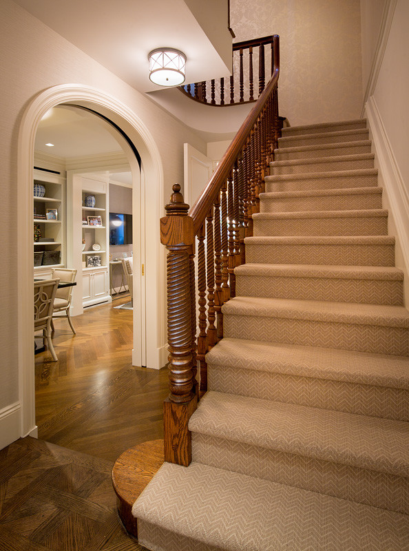 Photo of a large classic carpeted straight wood railing staircase in New York with feature lighting.