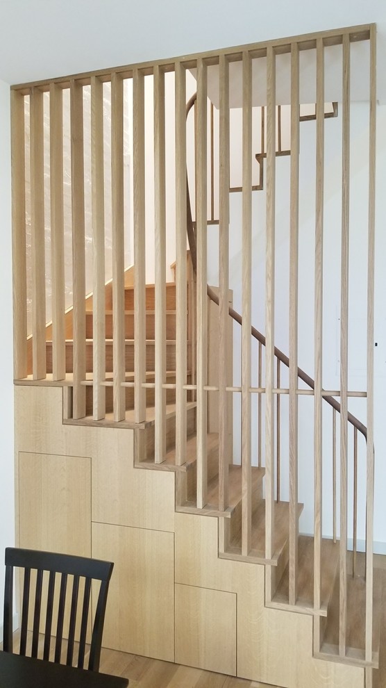 Imagen de escalera curva minimalista de tamaño medio con escalones de madera, contrahuellas de madera y barandilla de madera