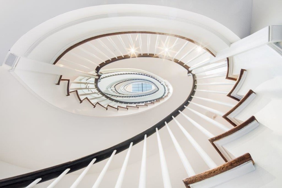 Imagen de escalera curva clásica renovada grande con escalones de madera y contrahuellas de madera pintada