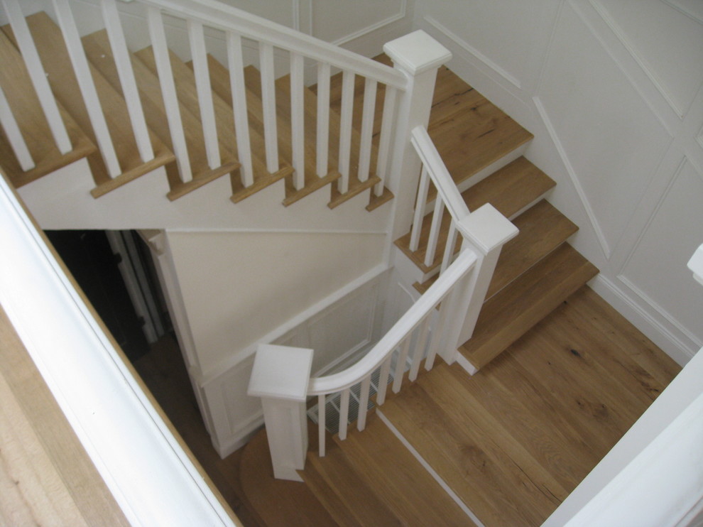 Ejemplo de escalera en U de estilo americano de tamaño medio con escalones de madera, contrahuellas de madera pintada y barandilla de madera
