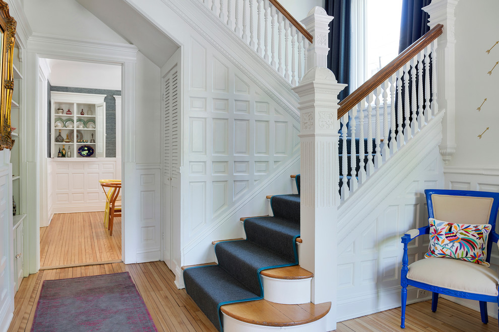 Diseño de escalera en U clásica con escalones de madera y contrahuellas de madera pintada